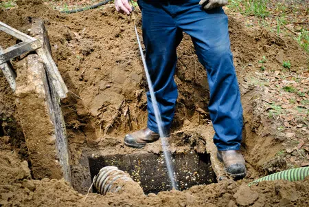 Worker in blue coveralls rinsing out an excavated tank opening — Si View Septic Pumping in North Bend